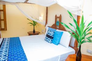 a bedroom with a bed with blue and white pillows at Baharini Beachfront Cottage in Malindi