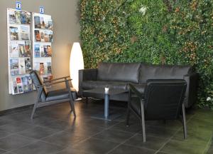 a couch and chairs in front of a green wall at Hótel Vellir in Hafnarfjördur