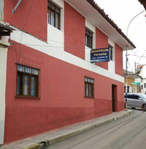 um edifício vermelho e branco ao lado de uma rua em Residencial Teresita em Vallegrande