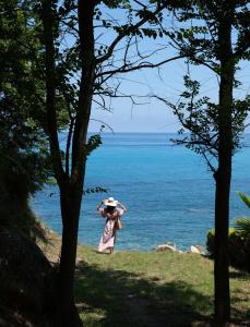 Eine Frau, die mit einem Sonnenschirm am Strand entlang geht. in der Unterkunft Infinity Resort Tropea in Parghelia