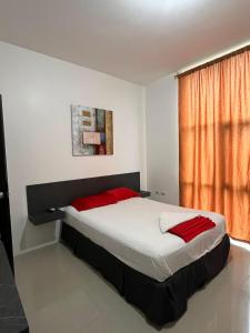 a bedroom with a bed with red pillows and a window at HOTEL AMASH Chone in San Pablo