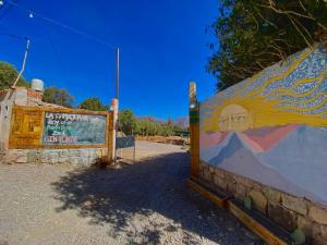 a wall with a painting on it next to a sign at Gran Casa Hostel&Camping in Tilcara