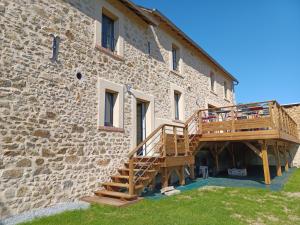 ein Steingebäude mit einer Holztreppe daneben in der Unterkunft CoGîte A Condat in Le Grand-Bourg