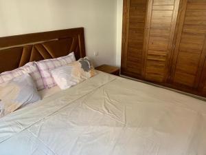 duże łóżko z drewnianym zagłówkiem i poduszkami w obiekcie Résidence Soltana, Marrakech w Marakeszu