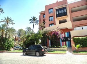 Résidence Soltana, Marrakech في مراكش: سيارة سوداء متوقفة أمام مبنى