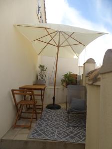 eine Terrasse mit einem Sonnenschirm, einem Tisch und Stühlen in der Unterkunft Studio 2 personnes à Moussan in Moussan