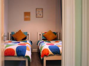 1 dormitorio con 2 camas y almohadas coloridas en Strawberry Fields Apartment, en Strangford