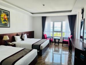 a hotel room with two beds and a desk at Gem Nha Trang Hotel in Nha Trang