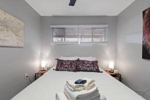 a white bedroom with a bed with towels on it at Loma Linda Courtyard Suites in Phoenix