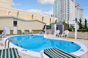 een zwembad met stoelen en een gebouw bij SureStay Hotel by Best Western Virginia Beach Royal Clipper in Virginia Beach