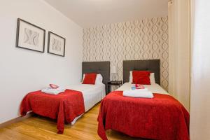 - une chambre avec 2 lits avec des draps rouges et publicité dans l'établissement Alcam Laforja, à Barcelone