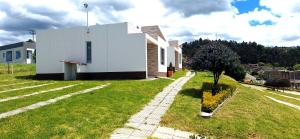 a small white house with a tree in the yard at Apartamento - ApartaSuite ARGUS in Paipa