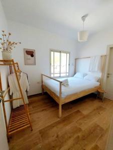 sypialnia z łóżkiem i drewnianą podłogą w obiekcie בקצה w mieście Ma'ale Gamla