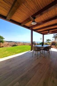 un patio con mesa y sillas en una terraza de madera en בקצה, en Ma'ale Gamla