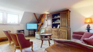 a living room with a couch and a tv at Le Clos de Charlotte in Colmar