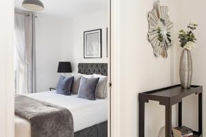 a bedroom with a bed and a table and a clock at Deanery Court Vittrum Suites in Southampton