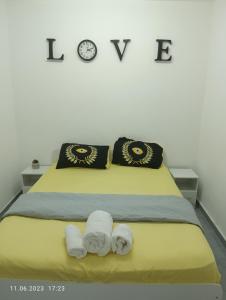 a bed with two towels and a clock on the wall at רימון יחידות אירוח Vacation units RIMON in Ashkelon