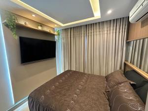 a bedroom with a bed and a flat screen tv at Lindo Apartamento Inteiro Proximo ao Centro de Criciuma in Criciúma