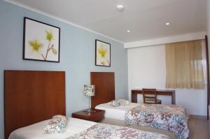 a hotel room with two beds and a window at Apartamentos Vila Nova in Vila Nova de Milfontes