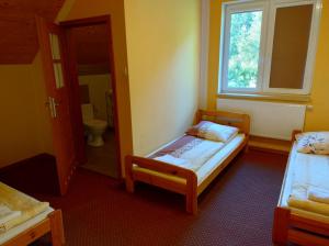 a small bedroom with two beds and a window at PENSJONAT W LESIE in Tuczno