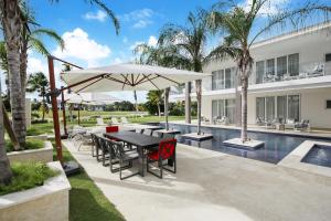 a patio with a table and umbrella next to a pool at Exquisite Contemporary 8BR Pool Villa with Chef, Butler, Maid, and Eden Roc Beach Club Access in Punta Cana