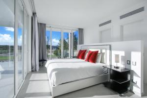 a white bedroom with a large bed with red pillows at Exquisite Contemporary 8BR Pool Villa with Chef, Butler, Maid, and Eden Roc Beach Club Access in Punta Cana