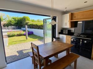 a kitchen with a table and a view of a garden at Hope Thatch in Salcombe