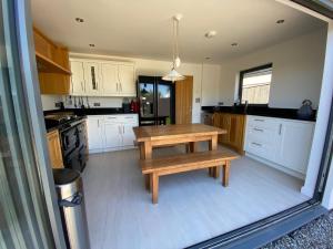 a kitchen with white cabinets and a wooden table at Hope Thatch in Salcombe
