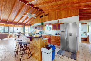 eine Küche mit einem Kühlschrank aus Edelstahl und Holzschränken in der Unterkunft Casa Garrobo in Dominical