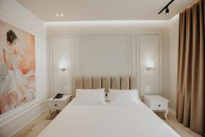 Un dormitorio con una gran cama blanca y una pintura en Seaside Hotel, en Vlorë
