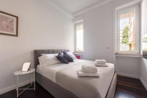 - une chambre blanche avec un grand lit et des serviettes dans l'établissement Bandello House, Corso Magenta - Milano, à Milan