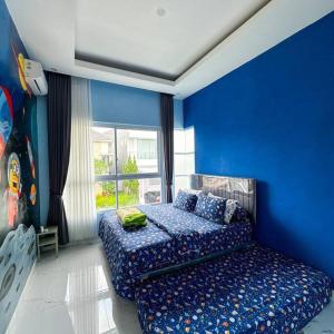 Cette chambre bleue comprend un lit et une fenêtre. dans l'établissement Villa 55 with Pool, Karaoke and Rooftop, à Bogor