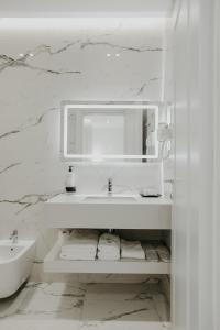 Baño blanco con lavabo y espejo en Seaside Hotel, en Vlorë