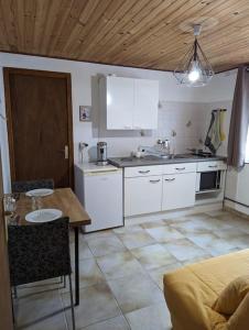 une cuisine avec une table et des placards blancs dans l'établissement Studio confort montagne, à Aulus-les-Bains