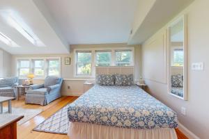 a bedroom with a bed and a chair and windows at Garden Cottage By The Sea in Manchester