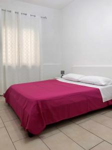 a large bed with a pink blanket on top of it at Marinella Casa Vacanze in Bacoli
