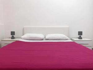 a white bedroom with a large bed with purple sheets at Marinella Casa Vacanze in Bacoli