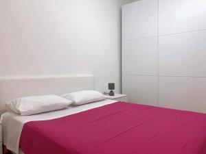 a white bedroom with a pink blanket on a bed at Marinella Casa Vacanze in Bacoli