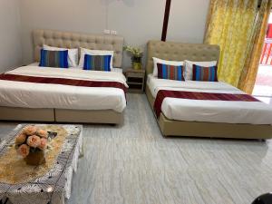 1 dormitorio con 2 camas y mesa en บุญจินดา รีสอร์ท, en Ban Phayom