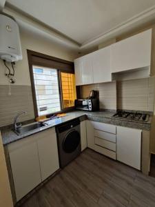 een keuken met witte kasten, een wastafel en een vaatwasser bij Very Nice Relaxing Apartment In Agadir El Houda in Agadir