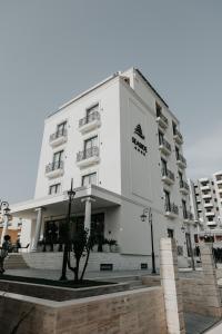 un edificio blanco con un árbol delante en Seaside Hotel, en Vlorë