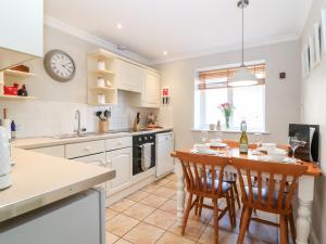 a kitchen with a table and chairs and a clock on the wall at Farm View Lodge in Stroud