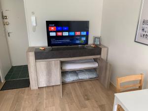 Un televisor sobre un soporte de madera en una habitación. en Mission 36 - Wifi - Calme et tranquillité - Résidence Beauséjour, en Troyes