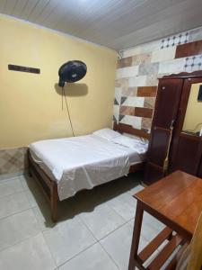 Habitación pequeña con cama y escritorio. en Hostal Yahuarcaca en Leticia