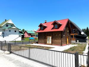 una casa de madera con techo rojo detrás de una valla en Дом в Жабляке с шикарным видом на Дурмидор en Žabljak