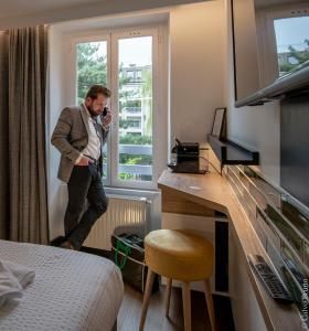 a man standing in a hotel room talking on a phone at 26 Faubourg - Ex-Hotel de Reims in Paris