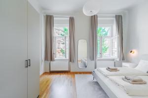 a white bedroom with two beds and two windows at Premium apartment - walking distance to city center in Graz