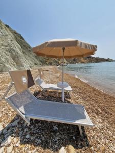 2 ligstoelen en een parasol op het strand bij Tendu' Punta Bianca Glamping Camp in Palma di Montechiaro