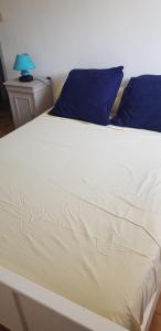 1 cama blanca grande con almohadas azules y lámpara azul en Charmant T3 en rez de jardin d'une villa, en Ghisonaccia