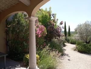 un pilar en un jardín con flores y árboles en Chambres d'hôtes Le Mas de Molines en Vogüé